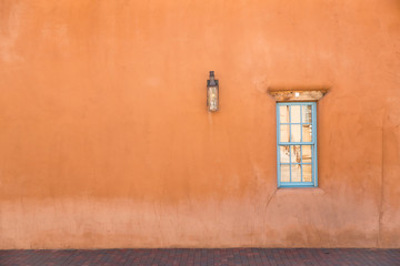 Fototapeta premium pomarańczowa ściana z turkusowym oknem w Santa Fe w Nowym Meksyku