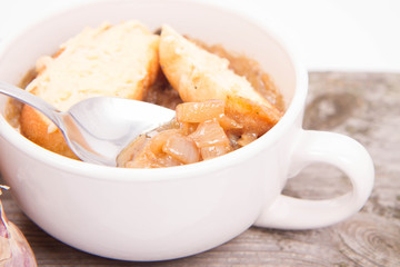 Onion soup with toast on a wooden background being eaten with a spoon