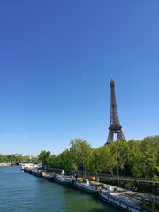 Fototapeta premium PARIS, FRANCE -APRIL 12, 2017 : spring view of Eiffel tower along the Seine river gate, and boats in tje seine river.