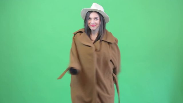 Attractive young woman dance in coat and than shows bikini. Greenscreen