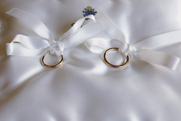 coppia di fedi nuziali legati su tessuto bianco © alex.pin