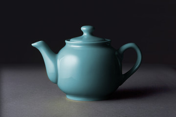 Blue ceramic teapot isolated on black background
