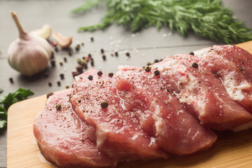 Juicy raw meat with spices, pepper, sea salt and herbs lies on a dark wooden background