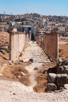 Giordania, 04/10/2013: lo skyline della moderna Jerash e il Decumano, la strada colonnata all'incrocio del Cardo Massimo nell'antica Gerasa, uno dei siti di architettura romana meglio conservati 