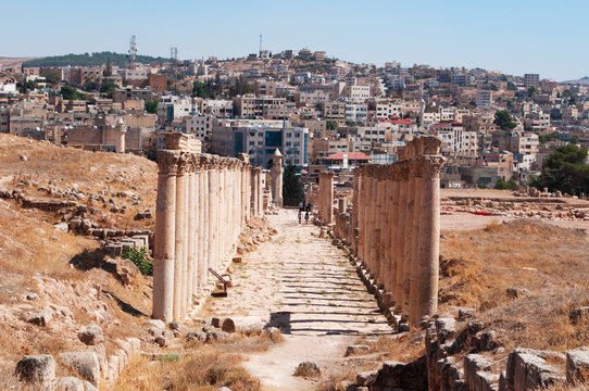 Giordania, 04/10/2013: lo skyline della moderna Jerash e il Decumano, la strada colonnata all'incrocio del Cardo Massimo nell'antica Gerasa, uno dei siti di architettura romana meglio conservati 