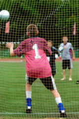 Little Boys playing soccer on the sports field next to goal