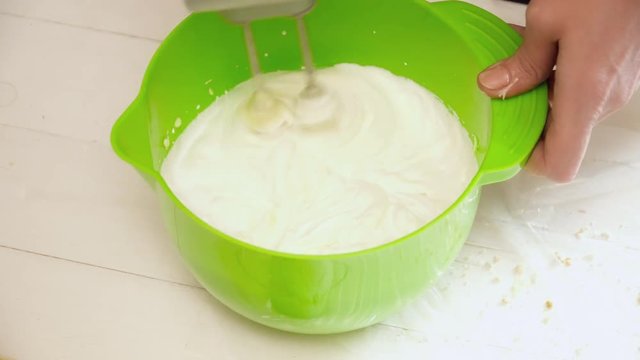 Woman's hands prepering the cream for the eclairs in the green bowl