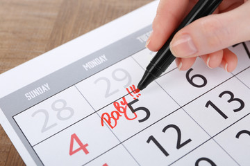 Woman writing BABY on date in calendar, close up