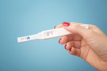 Pregnancy test in female hand on blue background