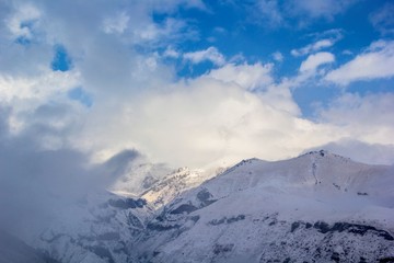 Fototapeta na wymiar Горный пейзаж, красивый вид на высокие снежные склоны, небо в белых облаках. Горы и природа Северного Кавказа, Грузия