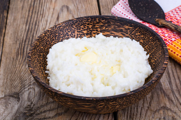 Milk rice porridge with butter in wooden bowl