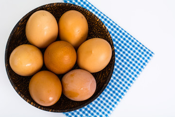 Chicken eggs in wooden bowl on white background