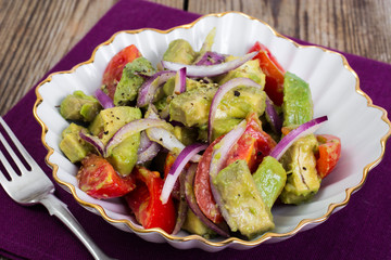 Salad with avocado and tomatoes on wooden background