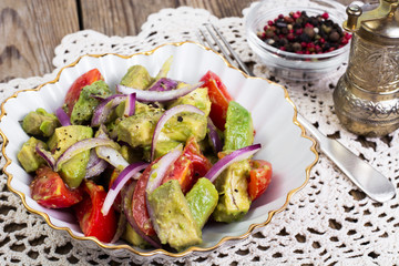 Salad with avocado and tomatoes on wooden background