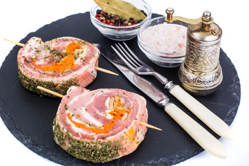 Roll of pork with spices for grilling on black stone
