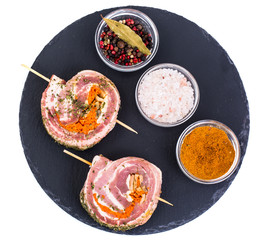 Roll of pork with spices for grilling on black stone