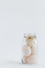 Decorative Glass Jar filled with White Duck Eggs against White Background