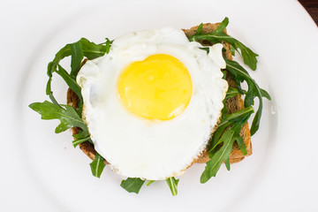 Breakfast toast with fried egg and arugula