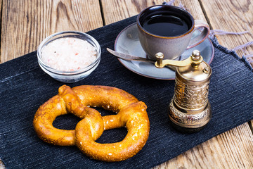 Pretzels with salt and black coffee on wooden background