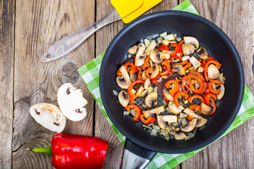 Fried mushrooms with peppers and onions in the pan. View from ab