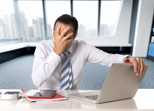 desperate senior businessman in crisis working on computer laptop at office desk in stress under pressure