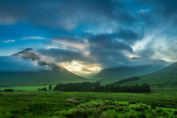 Fototapeta premium Mglisty zachód słońca nad górami Glencoe w Szkocji