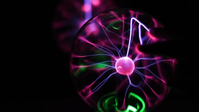 Closeup view of plasma ball with moving energy rays inside on black background