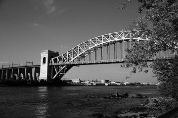 Fototapeta premium The Hell Gate Bridge behind the branches in black and white style, New York