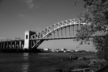 The Hell Gate Bridge behind the branches in black and white style, New York