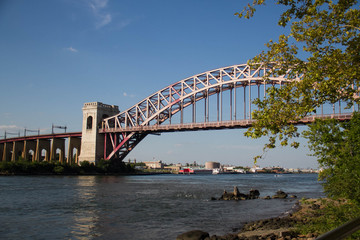 The Hell Gate Bridge behind the bench with blue sky, New York