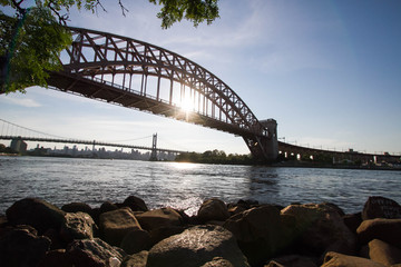 Obraz premium The Hell Gate Bridge, rocks and the sun reflect on the river, New York
