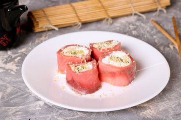 Finger food. Rolls of salmon with cream cheese close-up on the table horizontal