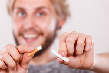 Smilling man is breaking a cigarette