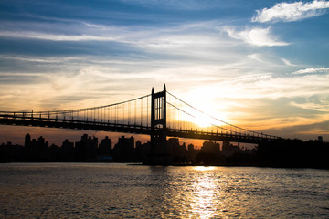 Silhouette of Triborough bridge over the river with sunset sky, New York