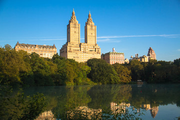 Buildings in Manhattan reflects on the lake at Central Park with blue sky, New York