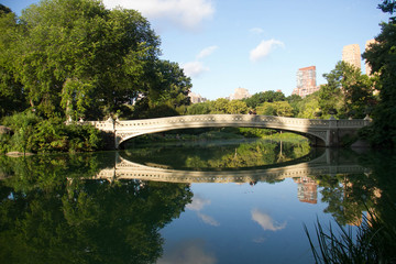 Fototapeta na wymiar Bow bridge and trees clearly reflects on the lake at Central Park with sky