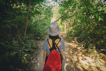 Back view of woman carry red backpack walking in the jungle