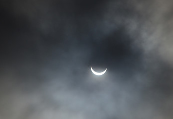 Obraz na płótnie Canvas Partial solar eclipse seen trough a layer of clouds.