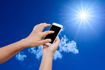Woman hand hold and touch screen smart phone on blue sky background