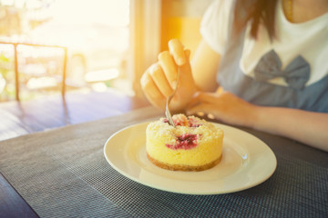 strawberry cheesecake with hand holding spoon  crepe  sauce on white plate.Crepe cake for dessert menu in coffee shop.vintage color