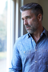 Mature Man Suffering From Depression Looking Out Of Window