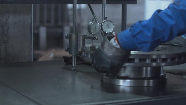 Factory worker inspecting a truck brake disc. 4K UHD