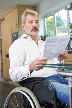 Frustrated Man In Wheelchair At Home Reading Letter