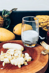 Glass of chia seeds pudding with mango. Basil seeds in coconut milk. A banch of bananas and a sliced banana on a table