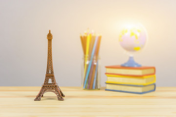 Eiffel tower statue and stack of book ,color pencil and globe on the school desk,knowledge school background education concept