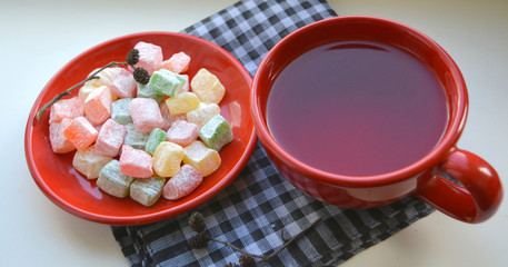 colorful Turkish Delight /Rahat Locum/ locum on a red plate with a cup of tea 