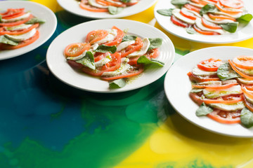 Белые тарелки с нарезанными овощами стоят на сине-желтом столе 