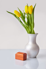 Spring flowers. Yellow tulips bouquet in a vase with a wooden gift box. Space for text. White background.