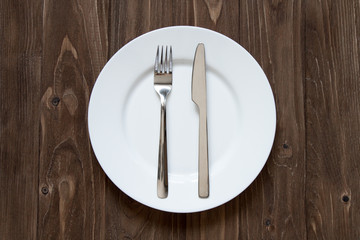 Plate and cutlery on wooden background in finished form