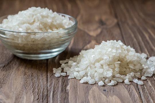 Sea sault in glass bowl and pule on wooden background
